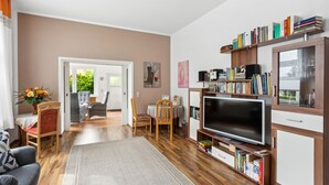 A modern living room with a flat-screen TV, wooden flooring, a bookshelf, and a dining area with chairs and a table. - Awesome apartment in Blankenburg (Harz) with WiFi (Blankenburg (Harz))