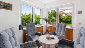 A corner room with two grey upholstered chairs, a small round table, and a view of a garden through large windows. - Awesome apartment in Blankenburg (Harz) with WiFi (Blankenburg (Harz))