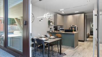 A modern kitchen with a dining area, a built-in island, and a view through a glass door.