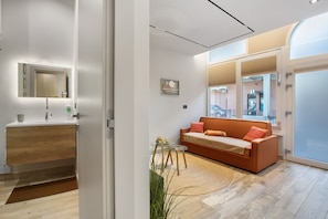 A modern interior with a wooden vanity, a glass table, a sofa with cushions, and a large mirror.