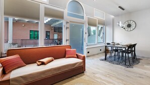 Een modern interieur met een bank, eettafel, stoelen en een klok aan de muur.