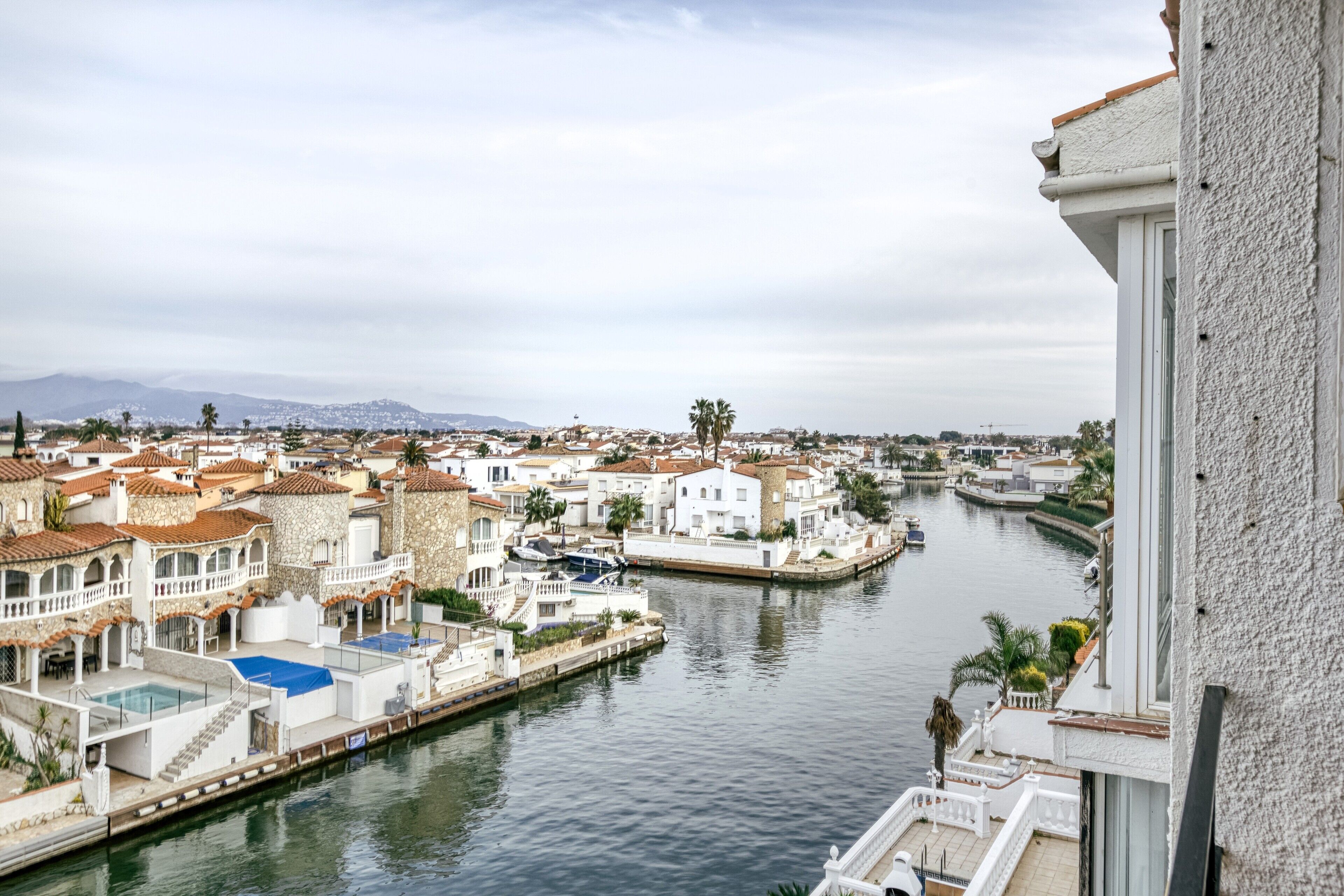 Une vue sur une ville, avec ses bâtiments, un quai et un bateau, le tout surplombant un canal.
