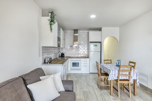 A compact kitchen with white cabinets, a built-in oven, and a refrigerator.