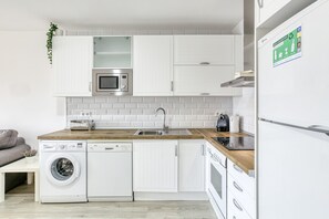 A modern kitchen with white cabinetry, a built-in microwave, a dishwasher, and a refrigerator.