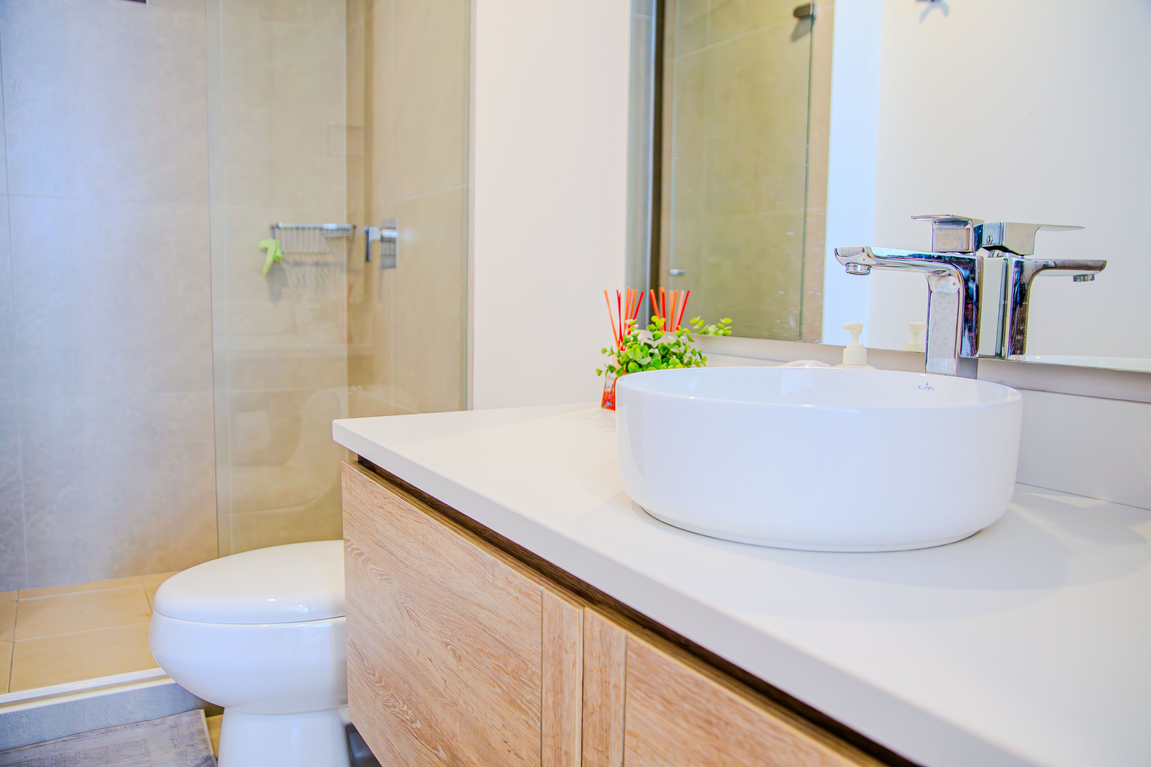 A modern bathroom with a white sink, a mirror, and a toilet.