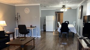 A spacious living area with a wooden coffee table, a dining table with chairs, a refrigerator, and a ceiling fan. - Coming into town for any special event.Cozy spacious space with all your needs!  (Mount Pleasant)