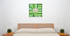 A bedroom with a wooden bed, two nightstands with lamps, a wall-mounted picture, and a small plant on each nightstand.