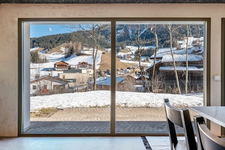 A room with a large window overlooking a snowy landscape with buildings and trees.
