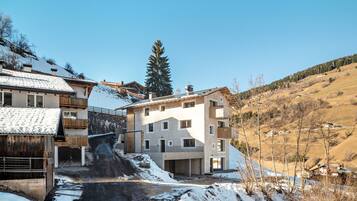 Ein modernes Gebäude mit mehreren Balkonen, einer Steinsäule und einer verschneiten Landschaft.