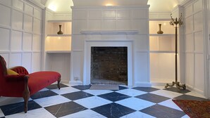A room with a checkered floor, a fireplace, and a red armchair.