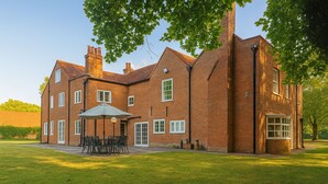 A large brick house with a spacious patio, a dining area with outdoor furniture, and a garage.
