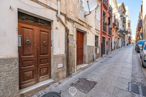 A narrow street with traditional buildings, large wooden doors, and satellite dishes.