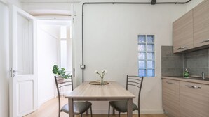 Cozinha moderna com mesa de madeira, duas cadeiras e janela com vidro azulado.