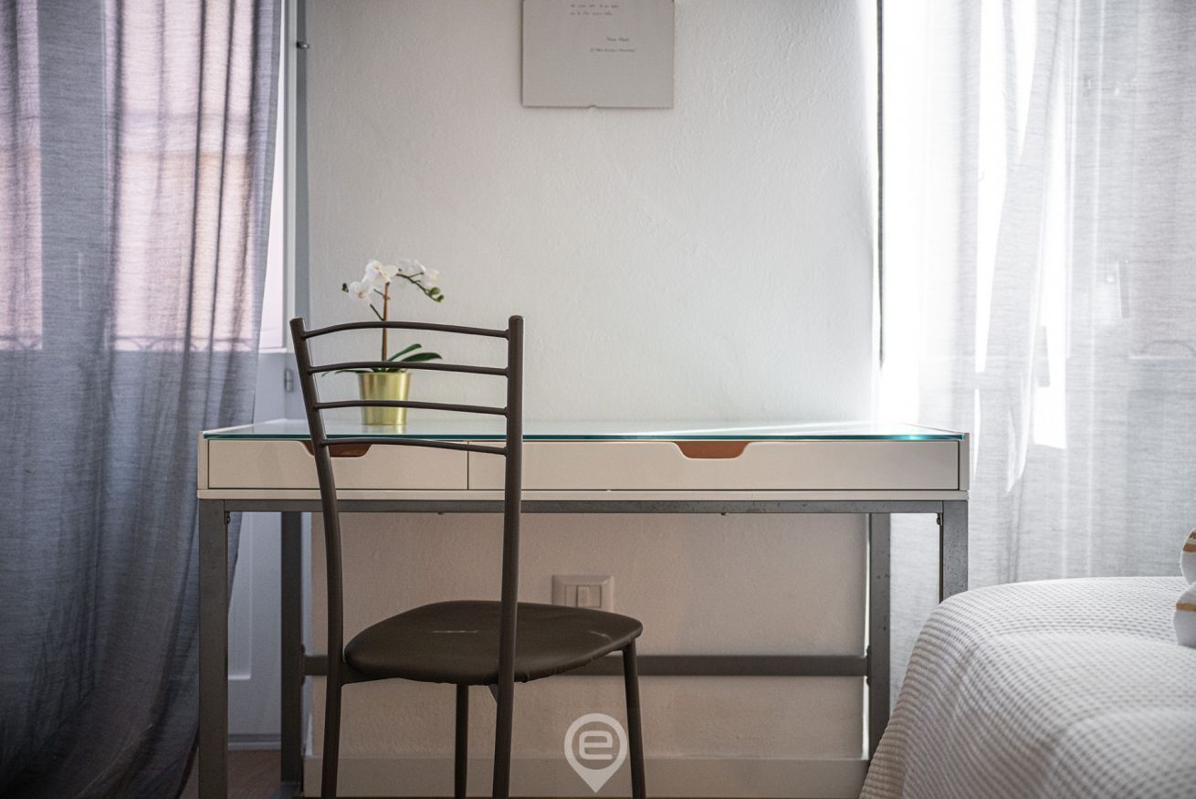 A room with a desk, chair, and bed.