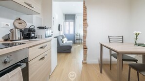 Una cocina moderna con zona de comedor, un sofá gris y una pared de ladrillo.