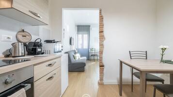 Une cuisine moderne avec un coin repas, un canapé gris et un mur en briques.