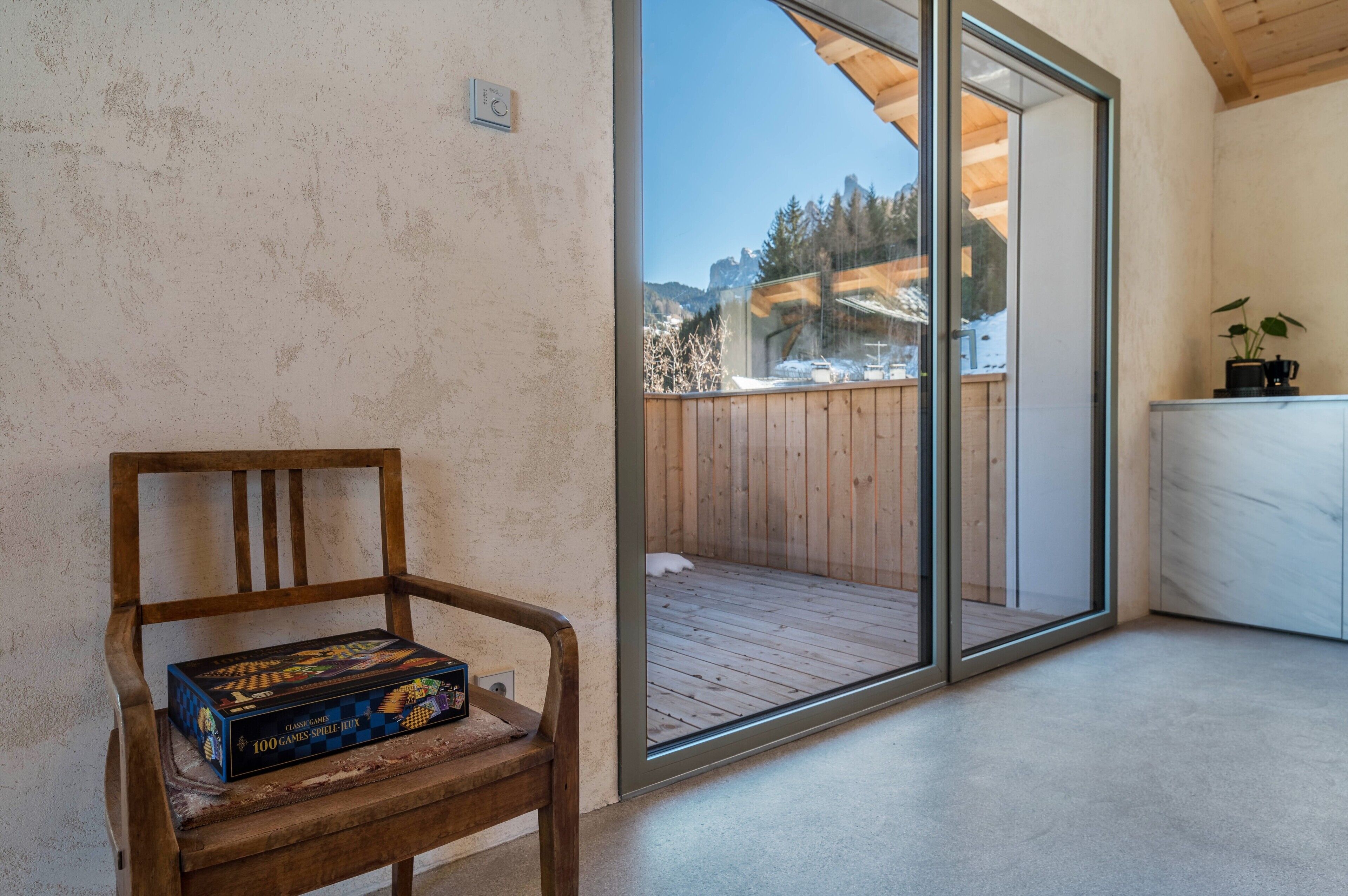 Eine Holzbank mit einem Gesellschaftsspiel, eine Glastür zu einem Balkon und ein Marmorunterschrank.