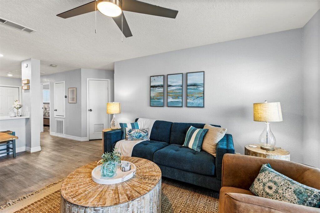 A modern living room with a dark blue sofa, a round coffee table, and a ceiling fan.