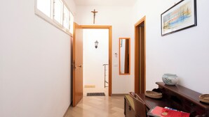 Un pasillo con puerta de madera, un cuadro enmarco, un espejo y una pequeña mesa con un cuenco y cestas.