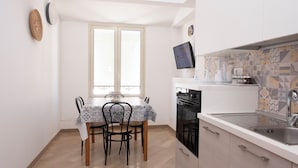 Una cocina funcional con mesa, sillas, televisor y lavamanos.