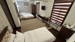 A hotel room with a bed, a desk, a chair, a radiator, and a TV mounted on the wall. - Hotel Grand Marakand (Samarkand)