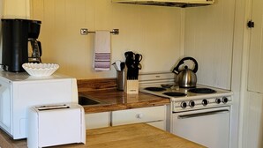 Une cuisine compacte avec un plan de travail en bois, une cuisinière blanche et une machine à café.