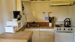 Une cuisine compacte équipée d’un four à micro-ondes, d’un grille-pain, d’un évier et d’une cuisinière.