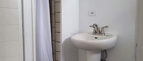Une salle de bain avec un lavabo blanc, un miroir et un rideau de douche.
