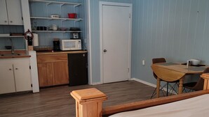Una habitación pequeña con cama, kitchenette y comedor.