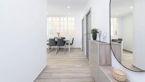 Un interior moderno con una zona de comedor, un mostrador de recepción y un espejo grande.