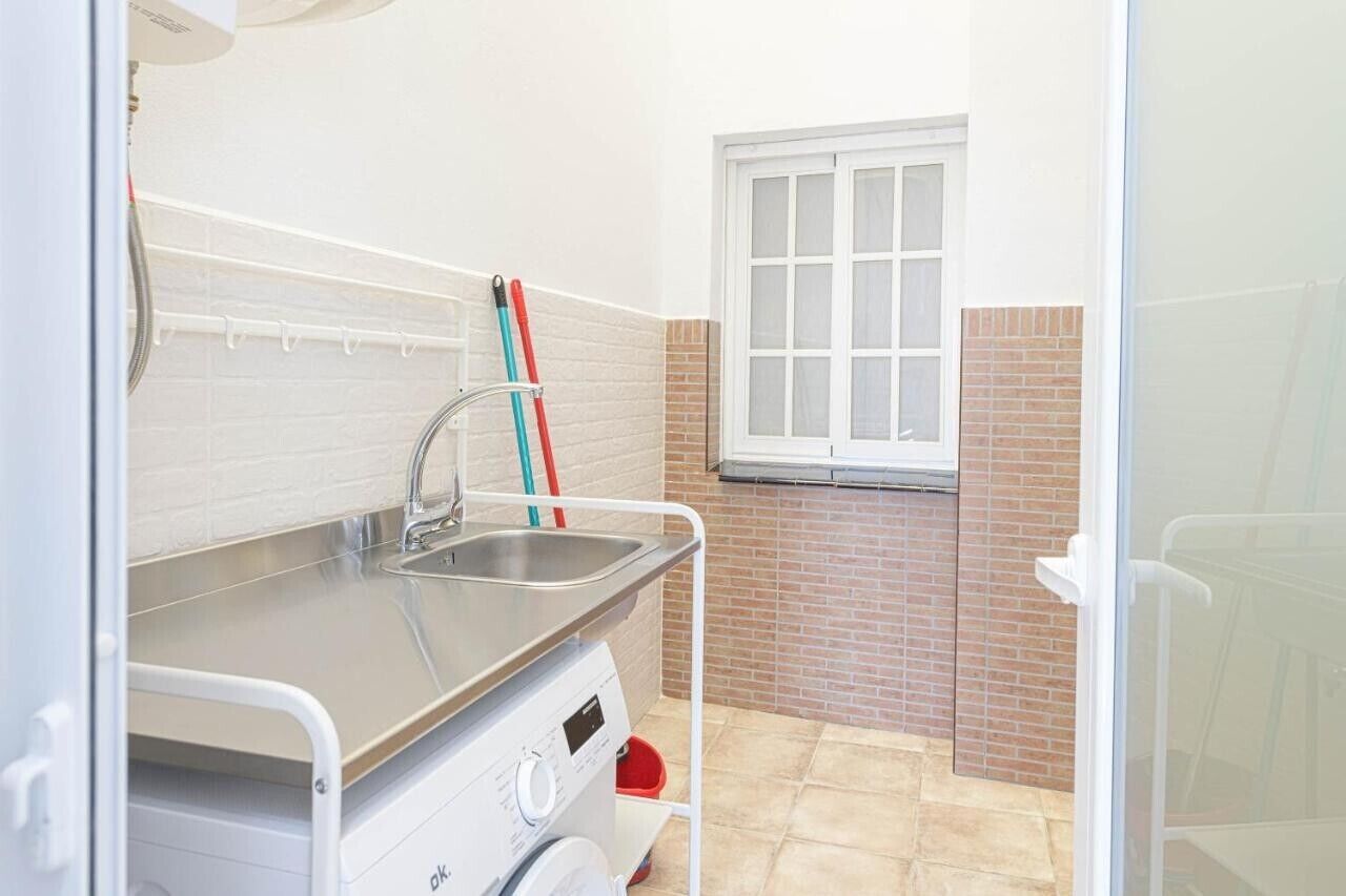 A compact kitchen with a sink, a small window, and a white door.