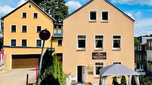 Un hotel con fachada amarilla, un letrero que dice "GOLDEN VILLAND" y un jardín bien cuidado con césped y parterres de flores.