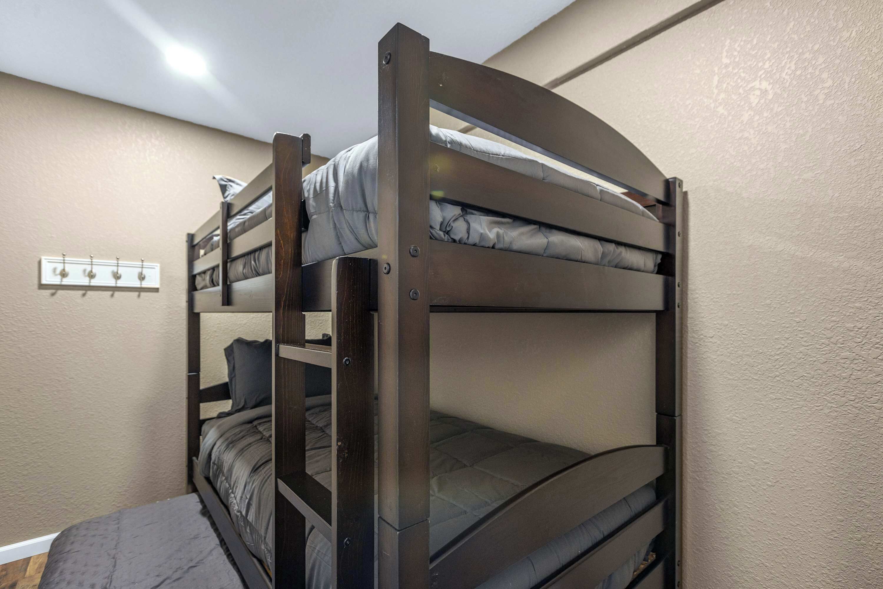 Een slaapkamer met een stapelbed met houten frame, een wandlamp en een kapstok.