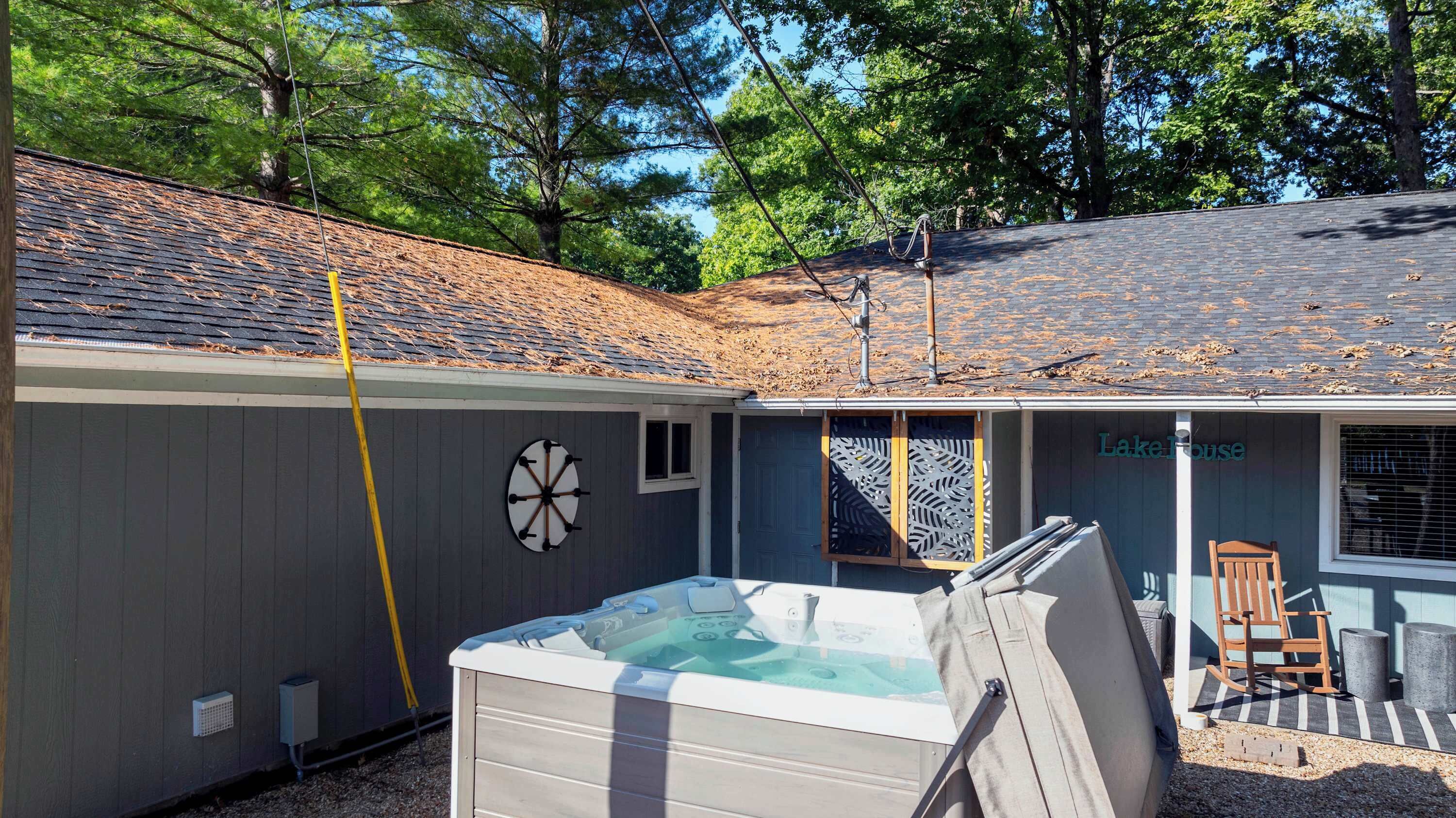 A backyard with a hot tub, a wooden deck, and a covered patio area.