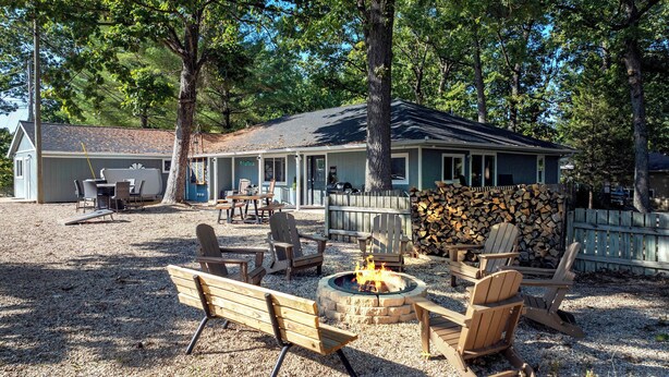 A cabin with a fire pit, outdoor seating, and a covered patio area. - White Oak Landing Spacious 6 BDR w/ Boat Slip! (Sunrise Beach)