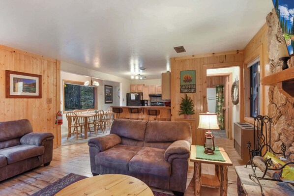 A cozy cabin interior with a living room, dining area, and kitchen. - Tahoe Pines Cabin (Homewood)