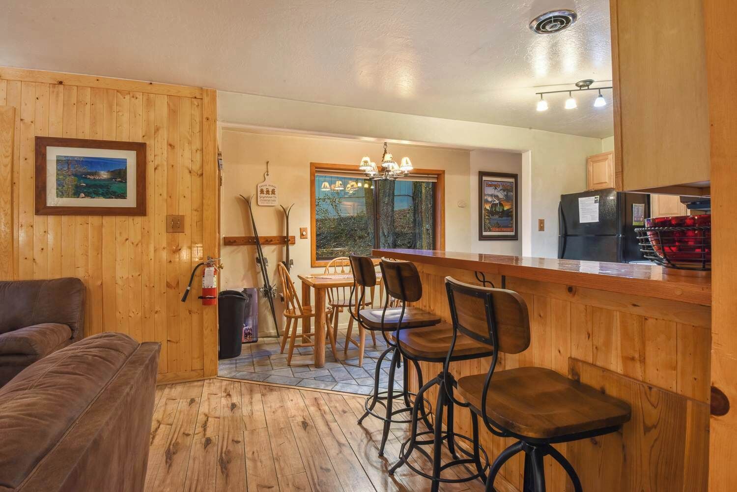 A wooden interior with a bar area, seating, and a view through a window.