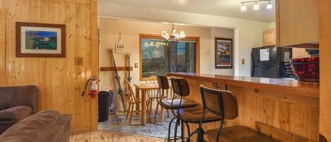 A wooden interior with a bar area, seating, and a view through a window.