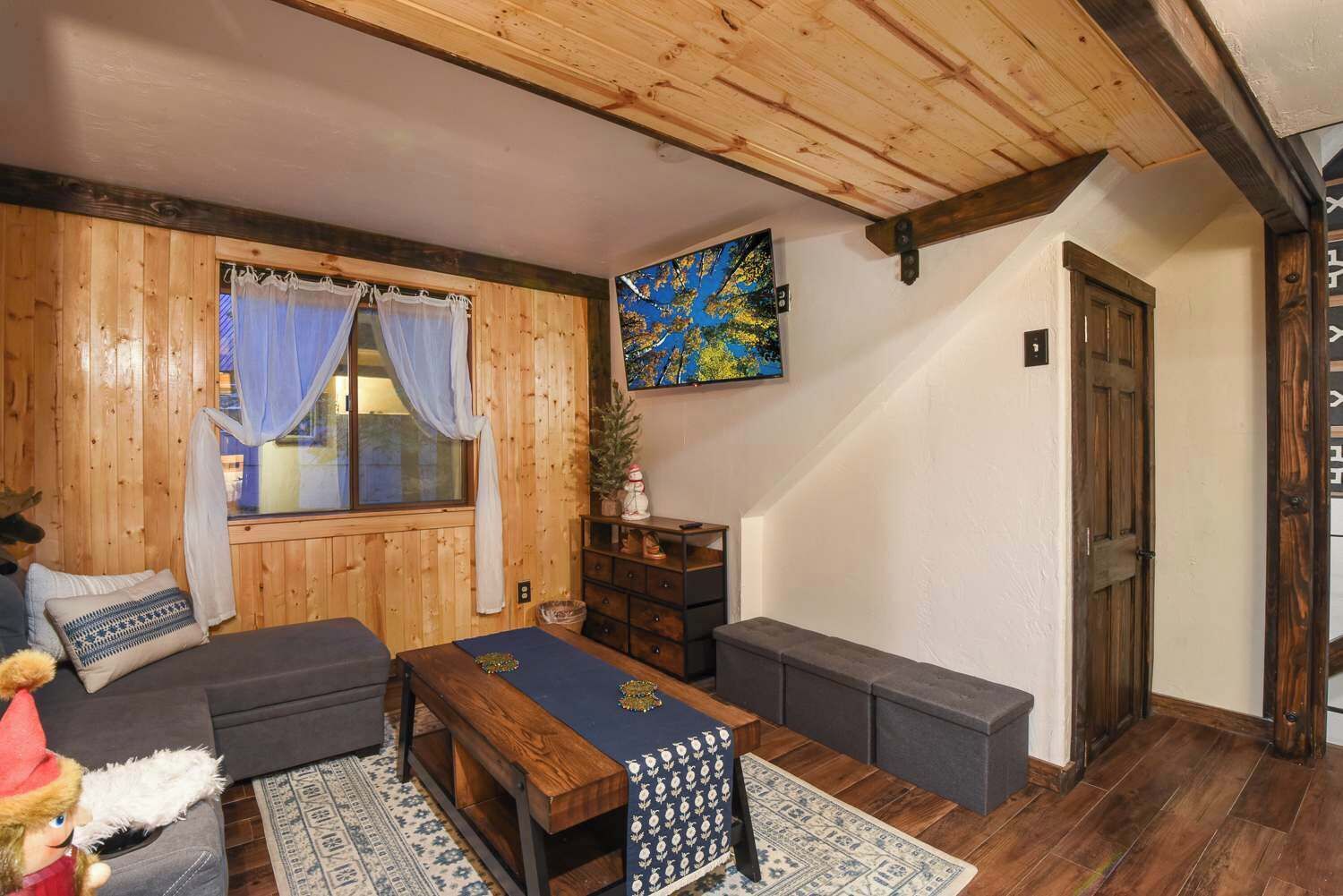 A cozy wooden cabin with a sofa, a table, and a bench.