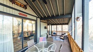 A covered outdoor area with a glass table, chairs, and a ceiling fan.