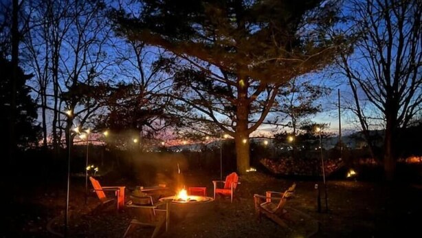 Un área de estar al aire libre con una chimenea y luces colgantes.