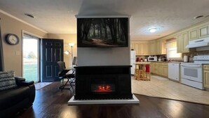 Una sala de estar con chimenea, comedor y cocina.