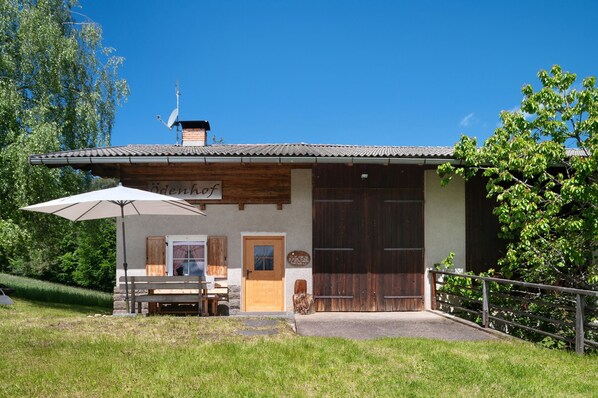 A rustic building with a wooden exterior, a large door, and a bench outside.