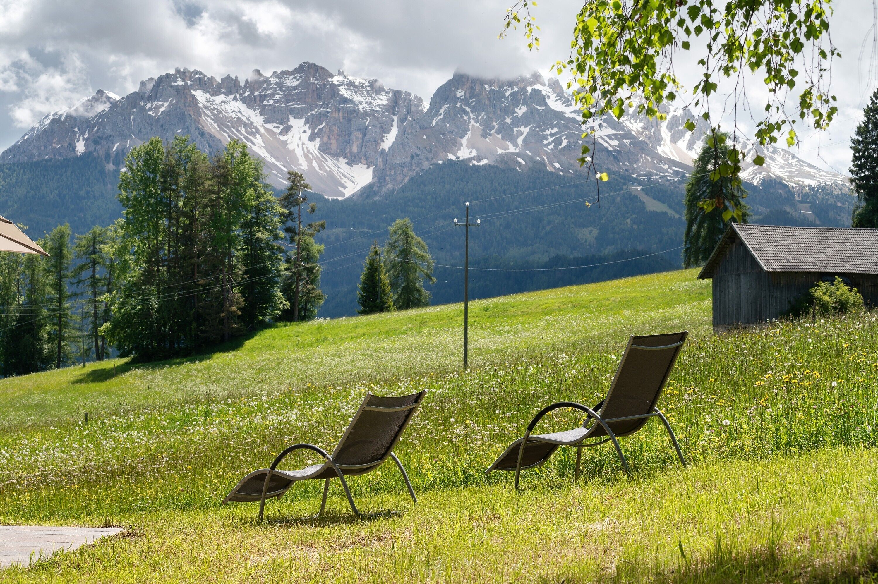 Two chairs in a grassy field with a mountain backdrop.