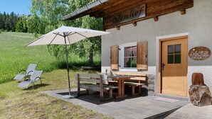 A wooden building with a bench and table outside, a door, and a sign.