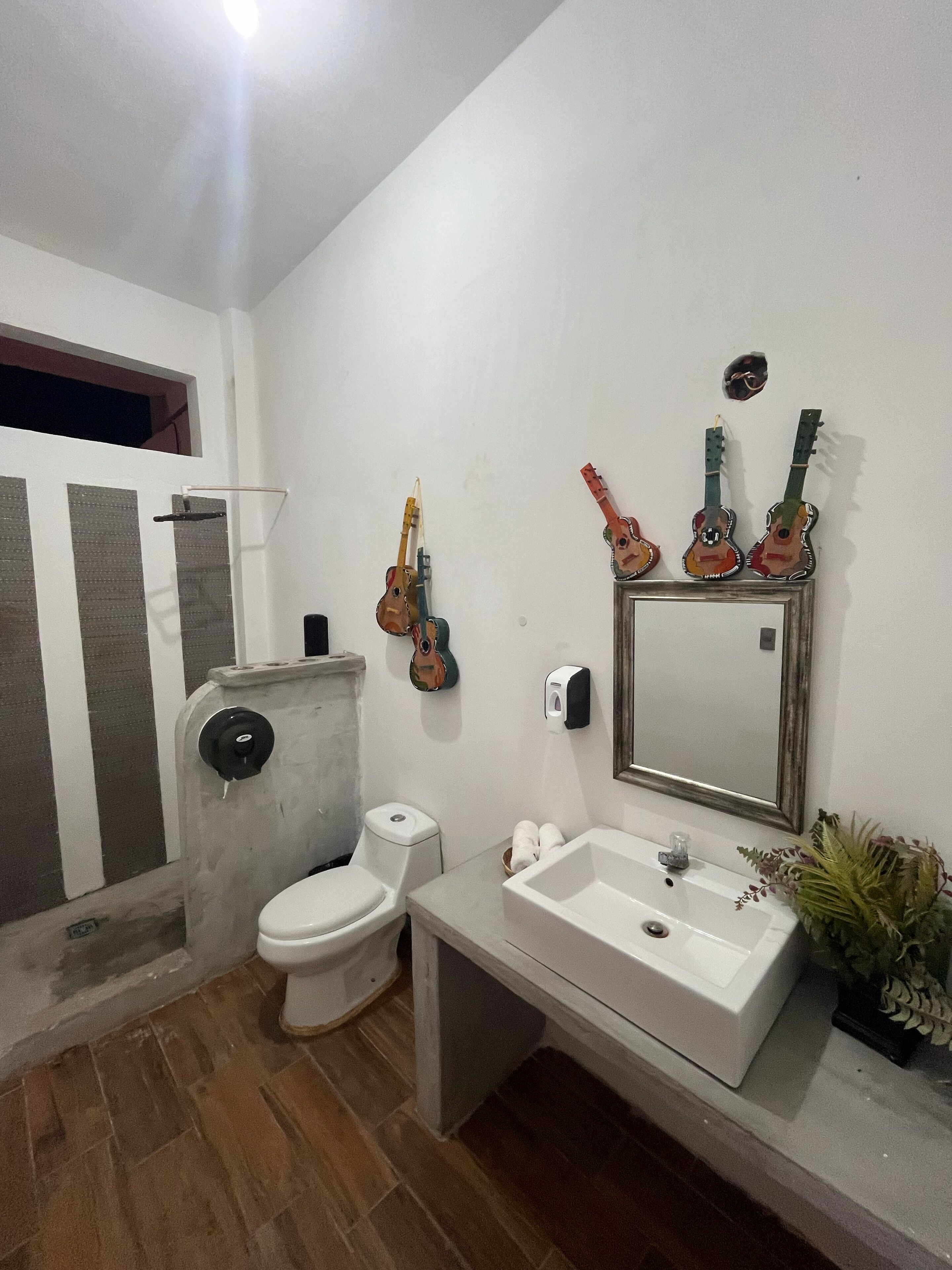 Un baño con inodoro, lavabo y espejo. Hay guitarras decorativas en la pared.