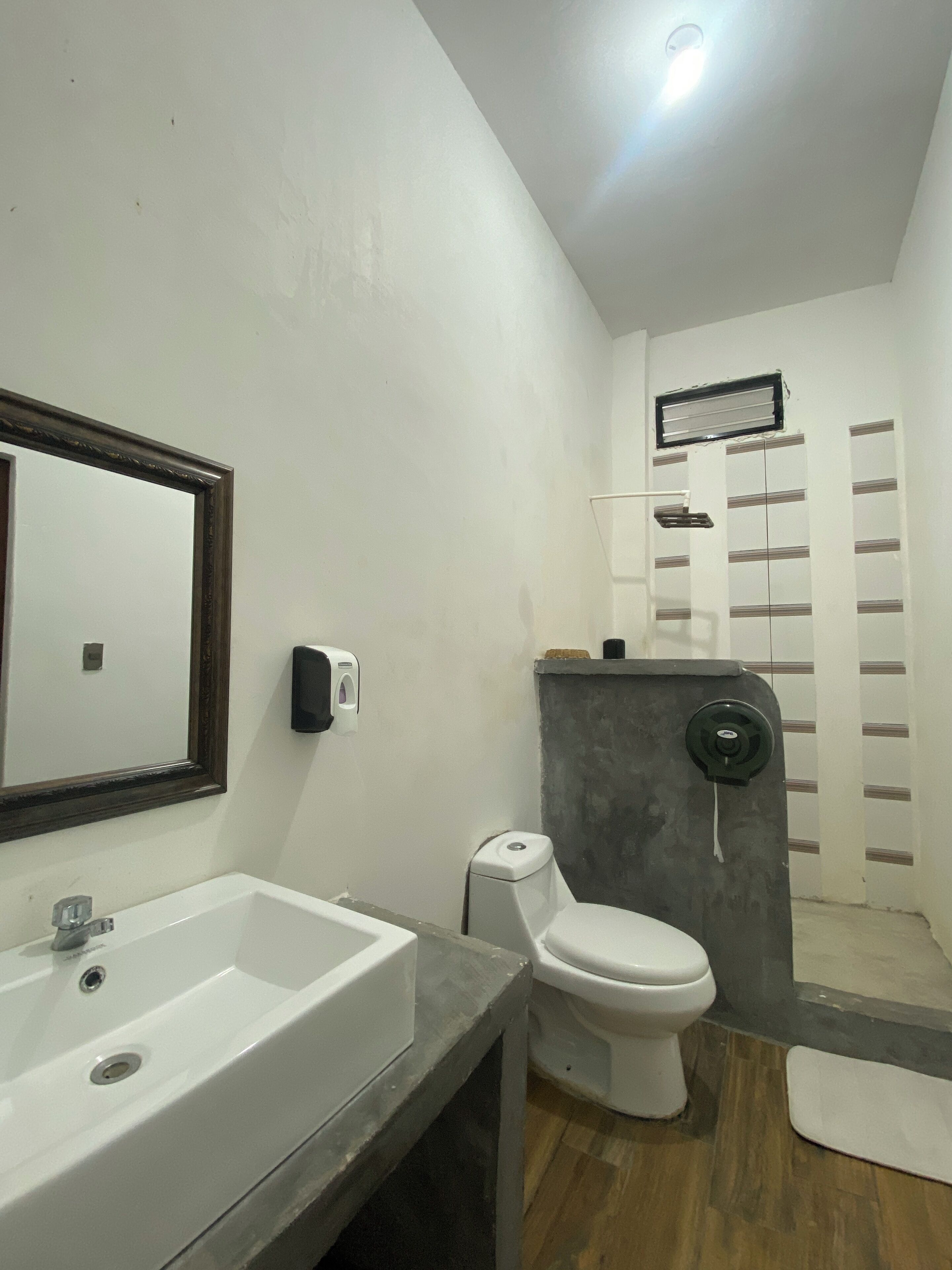 Un baño moderno con un lavamanos blanco, un inodoro y una zona de ducha.