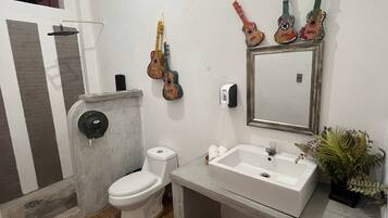 Une salle de bain avec des toilettes, un lavabo et un miroir. Il y a des guitares accrochées au mur.