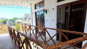 Un espacio al aire libre techado con barandilla de madera, suelo de concreto y luces colgantes.