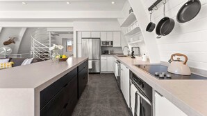 A modern kitchen with a central island, stainless steel appliances, and a hanging pot rack. - Mainstreet Masterpiece Stunning Views! (Park City)